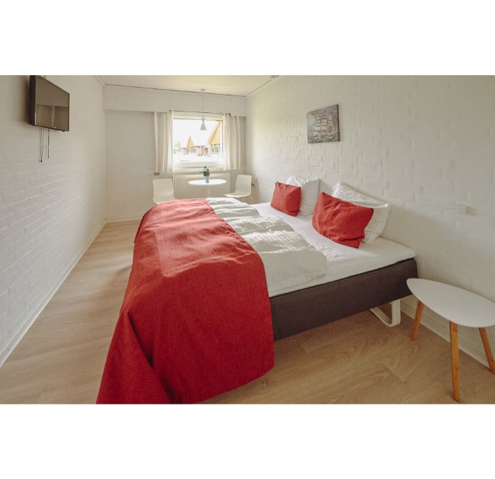 Billede af et hotelværelse med seng med rødt sengetøj